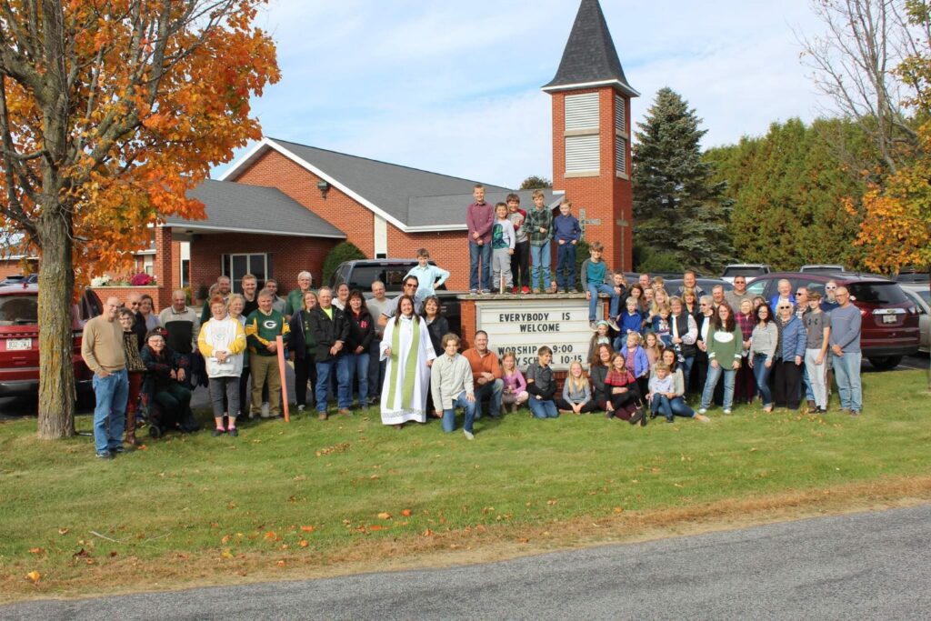 Parishioners outside St. John by all are welcome sign.